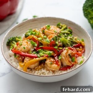 Shrimp stir fry served on top of rice with fresh broccoli in background.