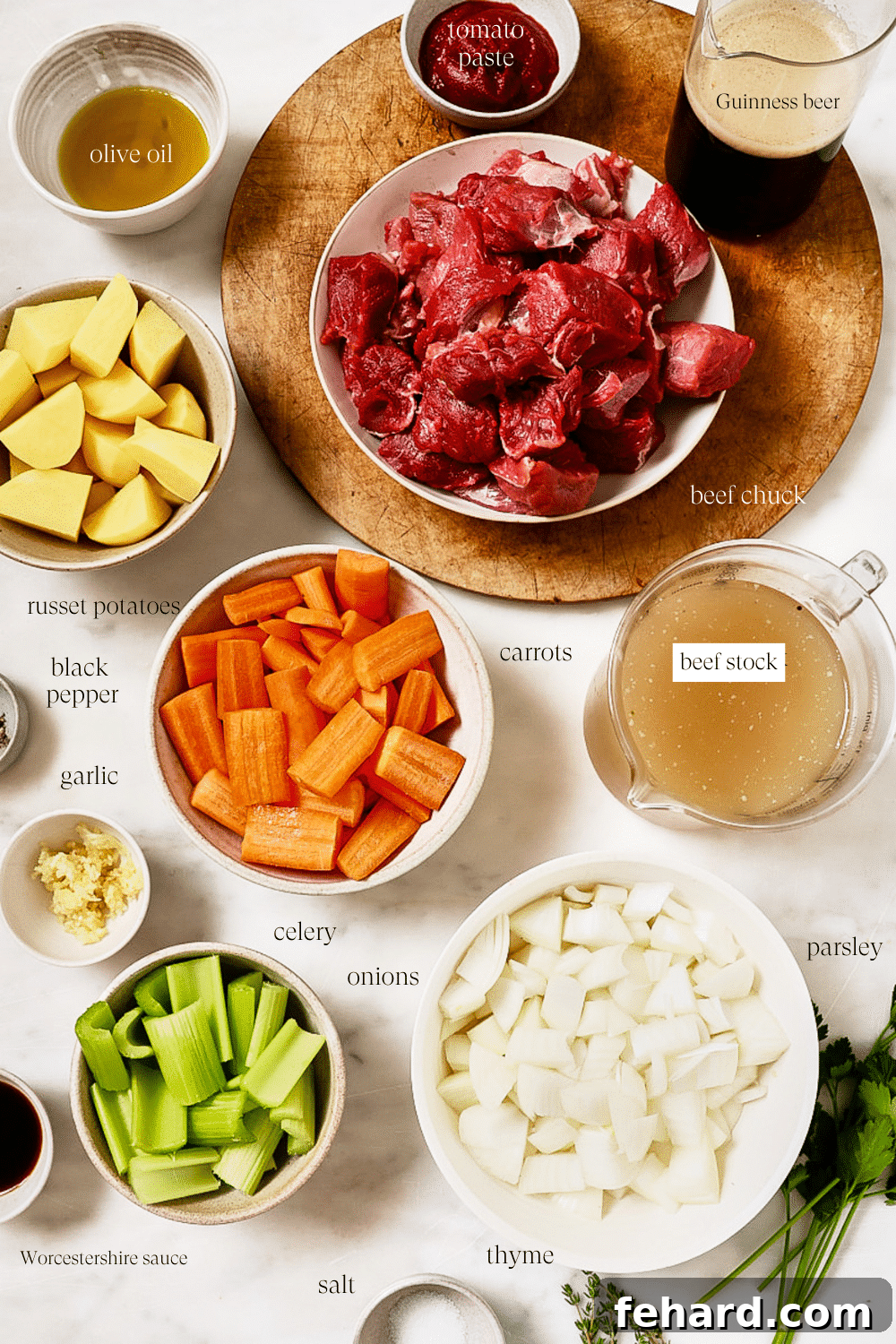Individual bowls containing perfectly measured portions of beef chuck, diced vegetables, a can of Guinness, and various seasonings, all meticulously prepped for cooking.