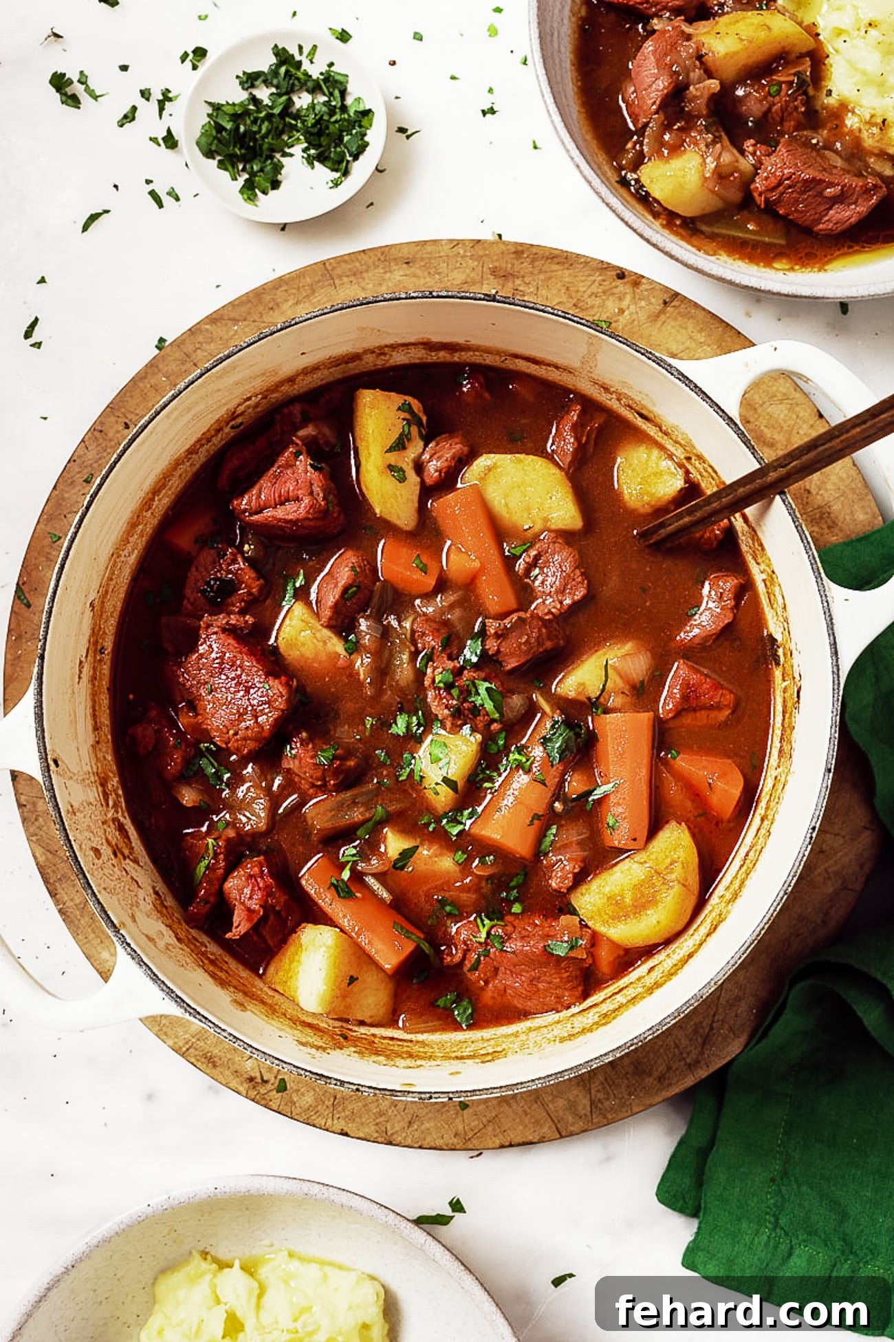 An overhead shot of the hearty Guinness Beef Stew served in a white Dutch oven, artfully garnished with fresh green parsley, ready to be enjoyed.