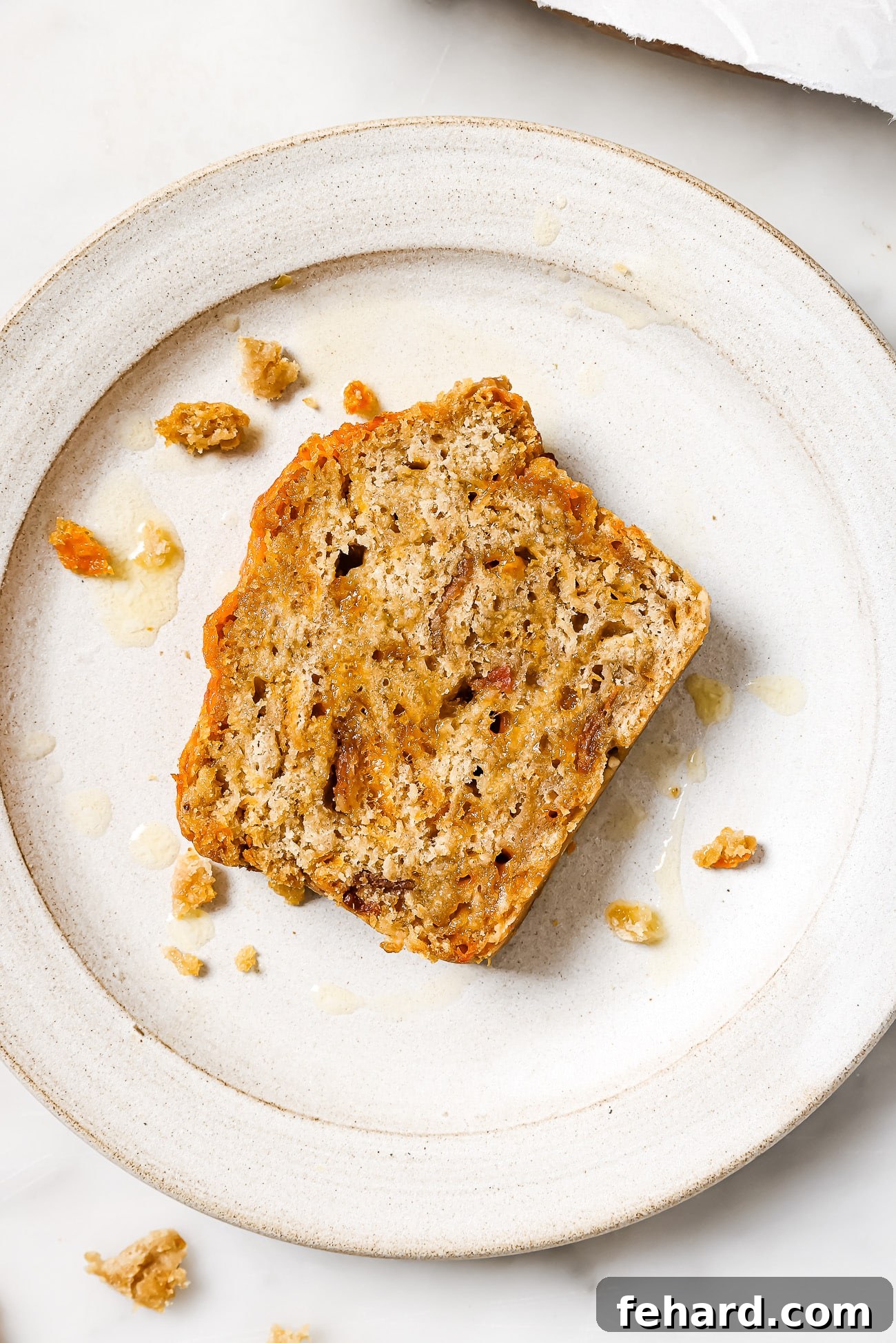 A beautiful slice of beer bread, showing its porous texture and the savory inclusions of bacon and cheese, served on a pristine white plate.