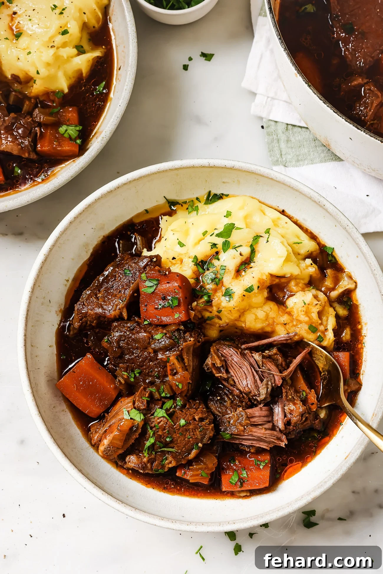 Guinness braised short ribs over mashed potatoes in a white bowl. 