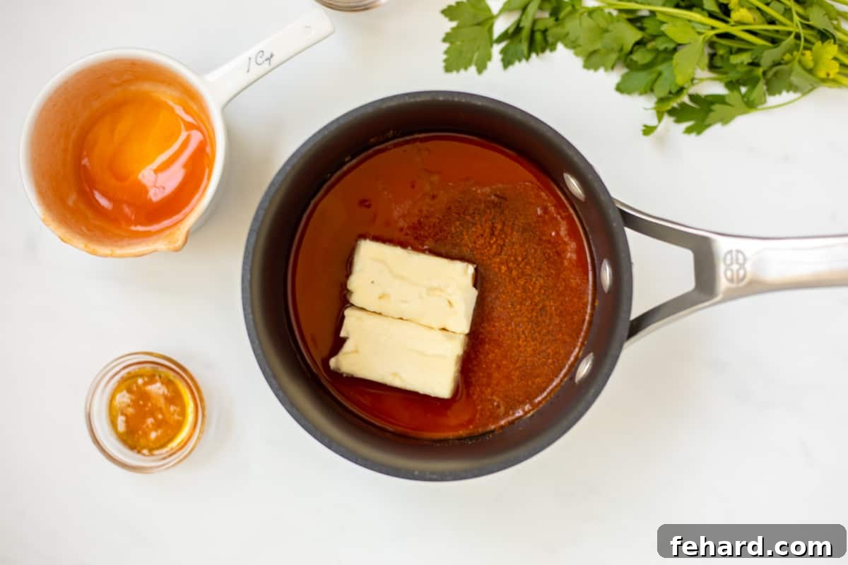 Close-up shot of ingredients for buffalo sauce being combined in a saucepan on the stove, showing the initial stage of cooking.