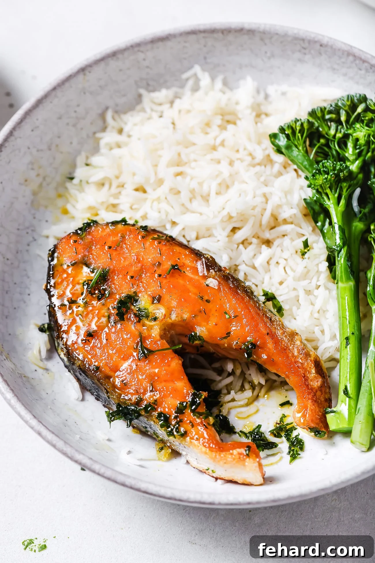 Garlic butter salmon steaks on a plate with rice and green vegetables.