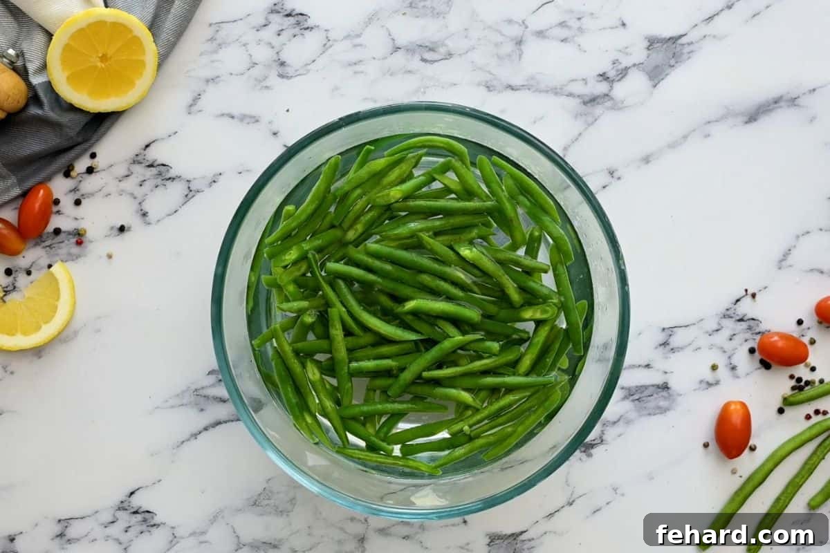 Freshly blanched green beans cooling in a bowl of ice water to preserve their crisp texture and vibrant color.