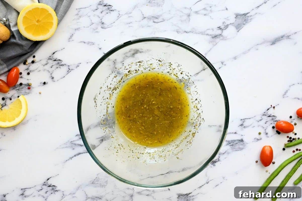 Homemade Italian dressing freshly whisked together in a clear glass bowl, ready to be combined with the salad ingredients.