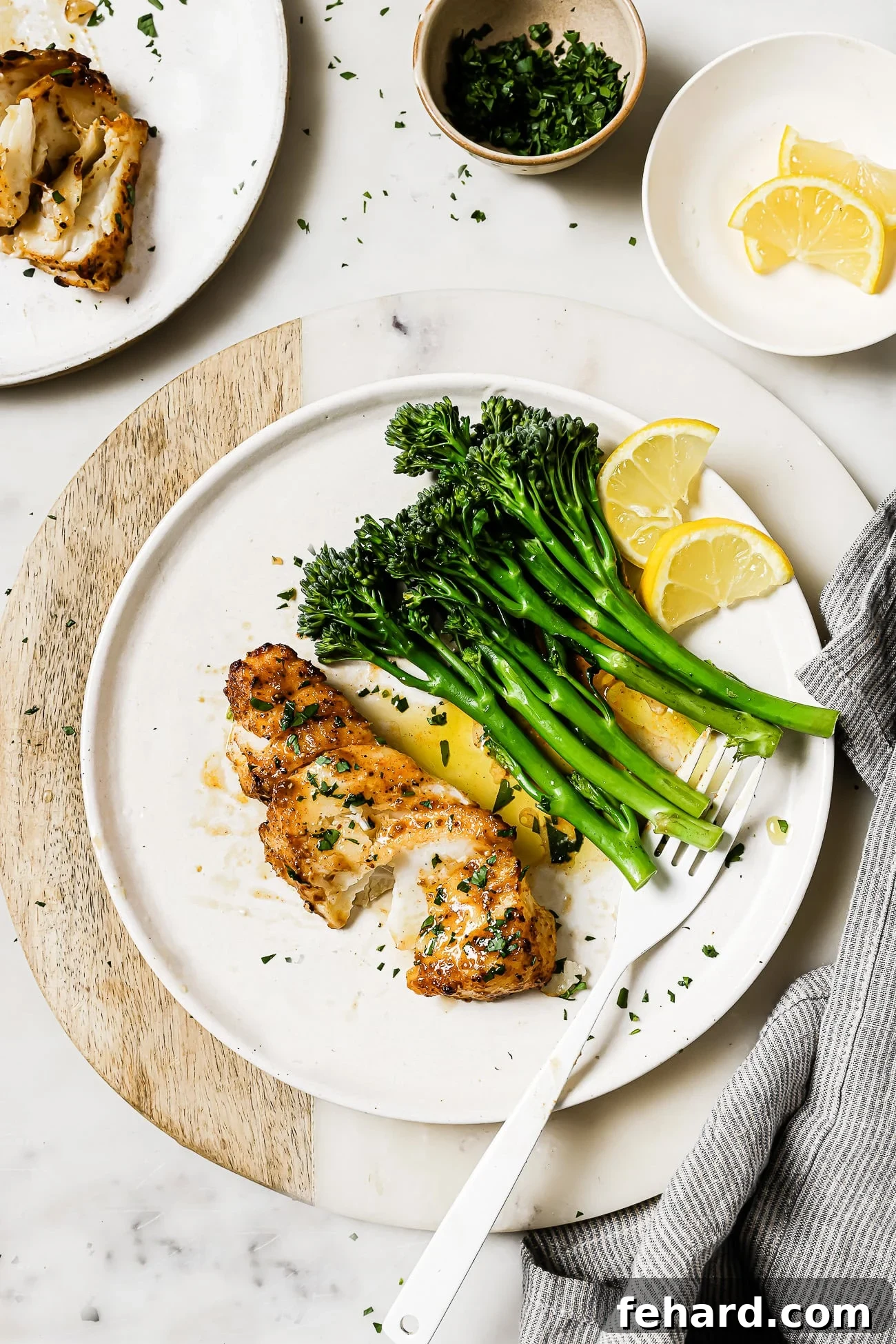 Delicious air fryer cod served on a white plate with fresh green vegetables and lemon wedges, ready to eat.