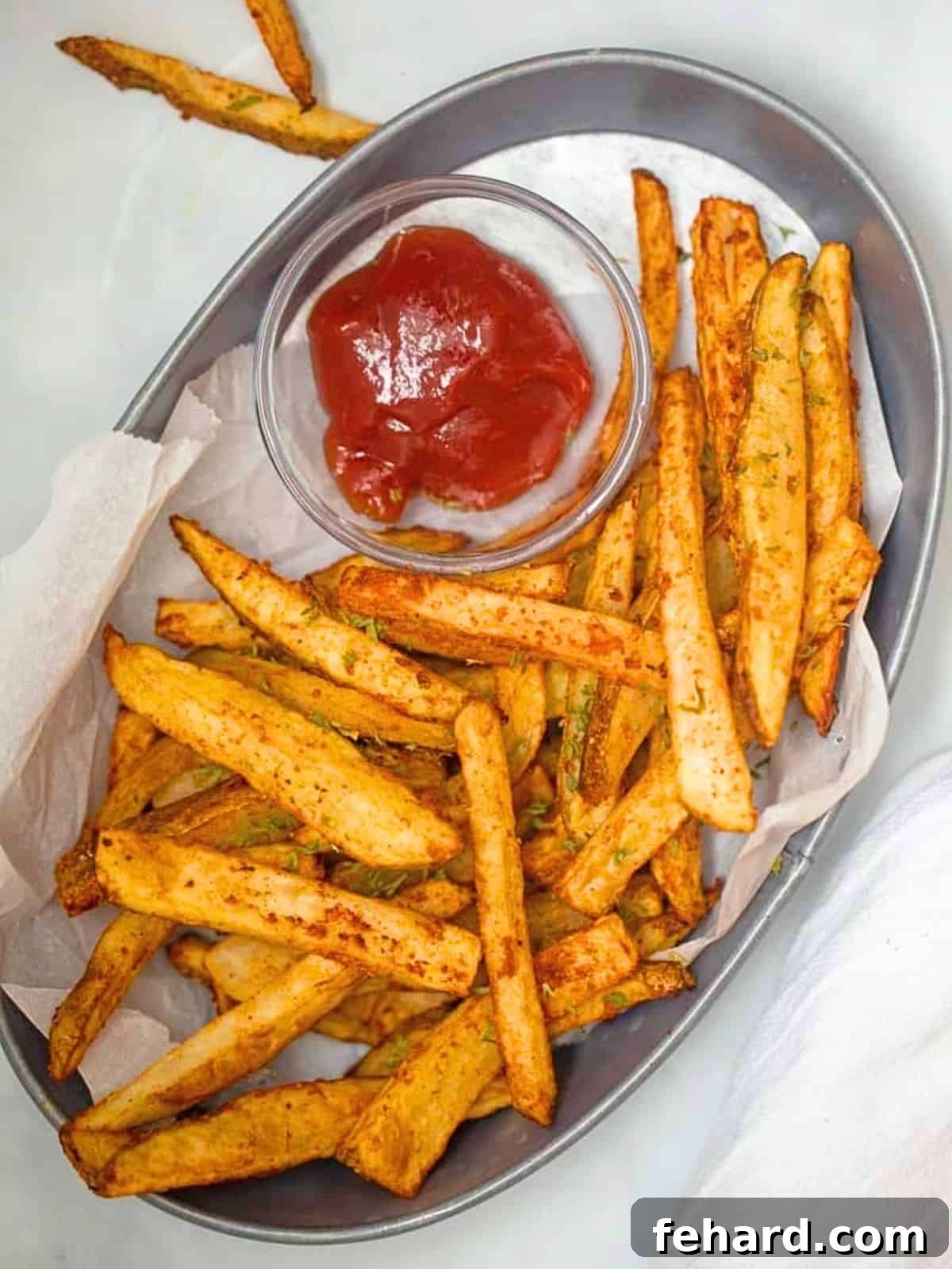 A rustic basket overflowing with perfectly golden and crispy air fryer homemade fries, accompanied by a small bowl of classic red ketchup, ready to be enjoyed.
