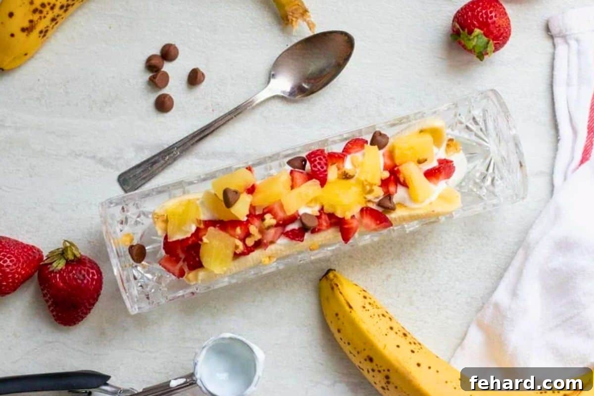 A vibrant and healthy banana split alternative, featuring a banana topped generously with creamy Greek yogurt, juicy fresh pineapple chunks, bright red strawberries, and a scattering of mini chocolate chips for a touch of indulgence.