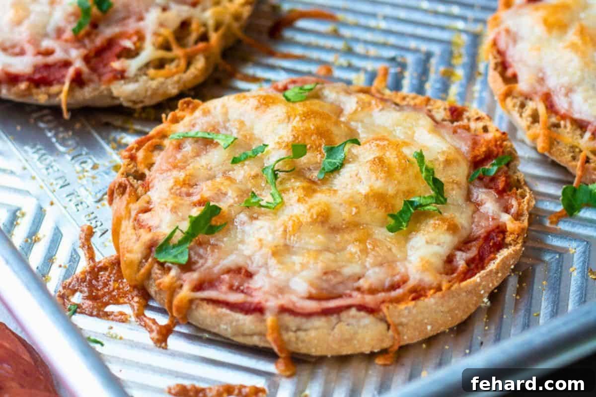 A freshly baked whole wheat mini pizza, golden and bubbly with melted cheese and a hint of sauce, resting on a sheet pan after being removed from the oven, ready to be enjoyed as a quick after-school snack.