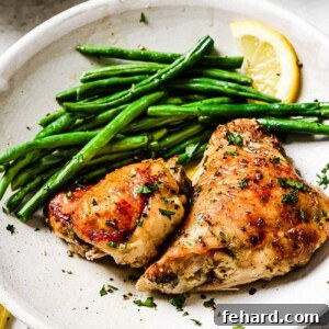 Lemon Chicken Thighs, perfectly roasted with golden skin and garnished with fresh herbs and lemon wedges.
