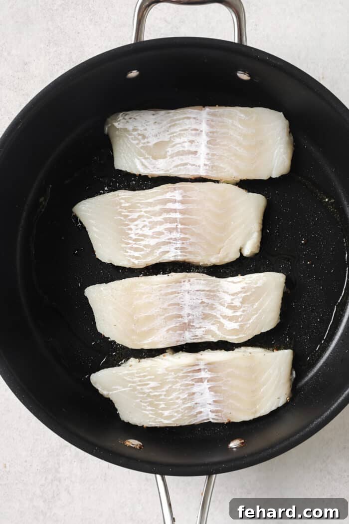 Pan-Seared Garlic Butter Haddock 5 raw Haddock fillets in a skillet