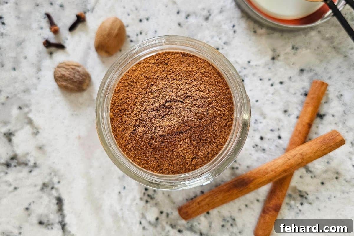 Small spice jar filled with homemade pumpkin pie spice blend, elegantly positioned next to cinnamon sticks and whole nutmeg, illustrating proper storage and fresh ingredients.
