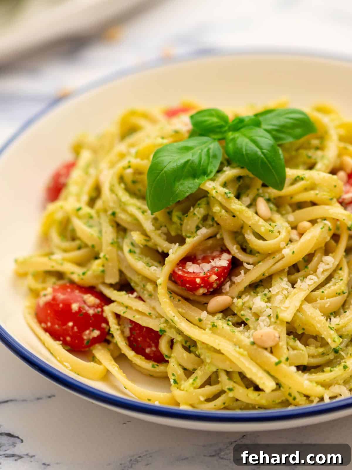 Bowl of pesto pasta tossed with fresh tomatoes and basil, garnished with extra Parmesan. A perfect easy pesto pasta dinner.