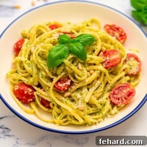 Bowl of pesto pasta tossed with fresh tomatoes and basil.