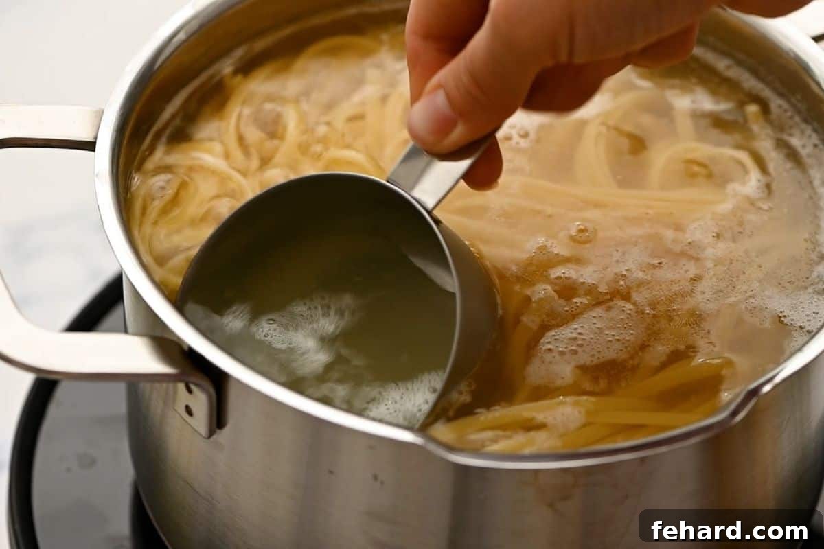 Measuring cup scooping out starchy pasta water from a pot of cooking linguine.