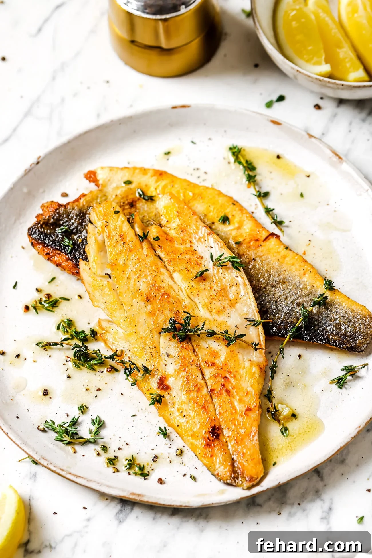 Succulent Garlic Butter Sea Bass Recipe 5 Garlic butter sea bass garnished with fresh thyme leaves on a white plate, ready to be served.