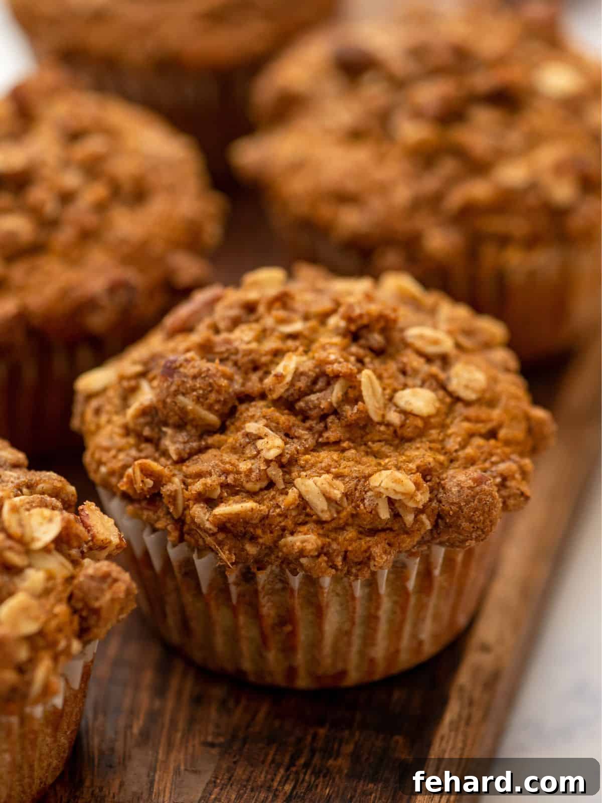 A perfectly baked Pumpkin Banana Muffin topped with a golden-brown streusel, resting on a rustic wooden cutting board.
