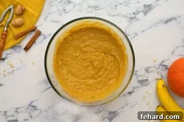 Rich pumpkin banana muffin batter resting in a mixing bowl, flanked by fresh bananas.