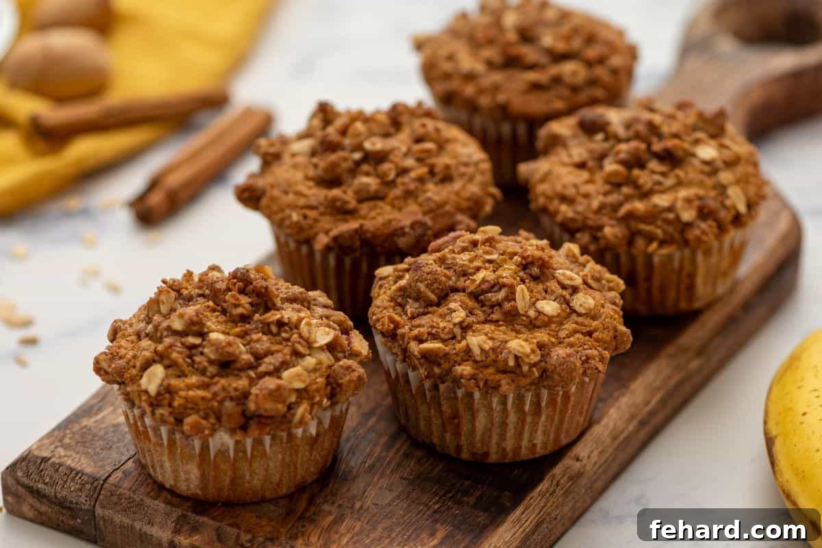 Freshly baked Banana Pumpkin Muffins cooling on a cutting board, with a whole banana beside them.