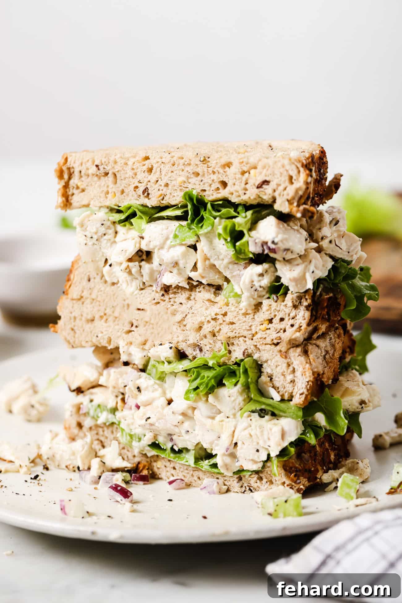 Signature Chicken Salad 8 Two halves of a chicken salad sandwich, perfectly sliced and arranged on a white plate, ready for consumption.