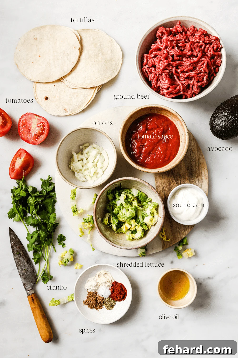 Prepped ingredients for ground beef tacos, including spices, tomato sauce, and ground beef, arranged neatly on a white marble countertop.