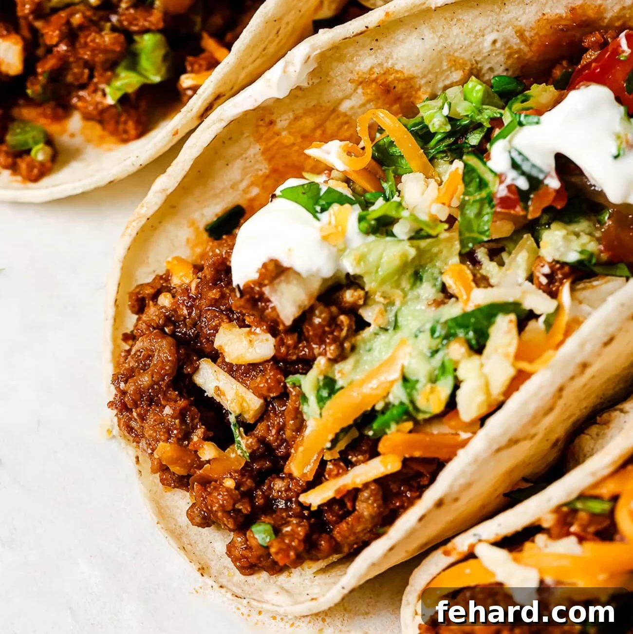 A close-up shot of freshly assembled ground beef tacos, ready to be enjoyed with a variety of colorful toppings.