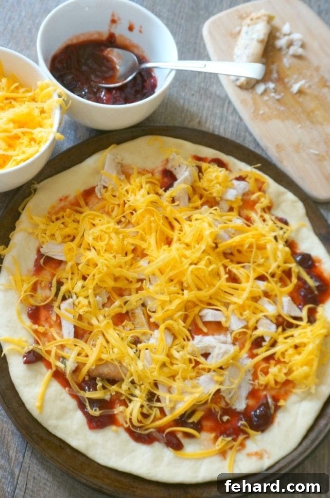 An assembled BBQ turkey pizza, generously topped with turkey and cheese, ready for the oven.
