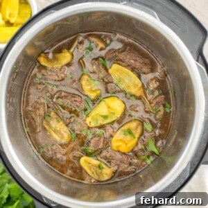 Cooked and shredded Mississippi pot roast in inner pot of Instant Pot topped with Pepperoncini Peppers and parsley.