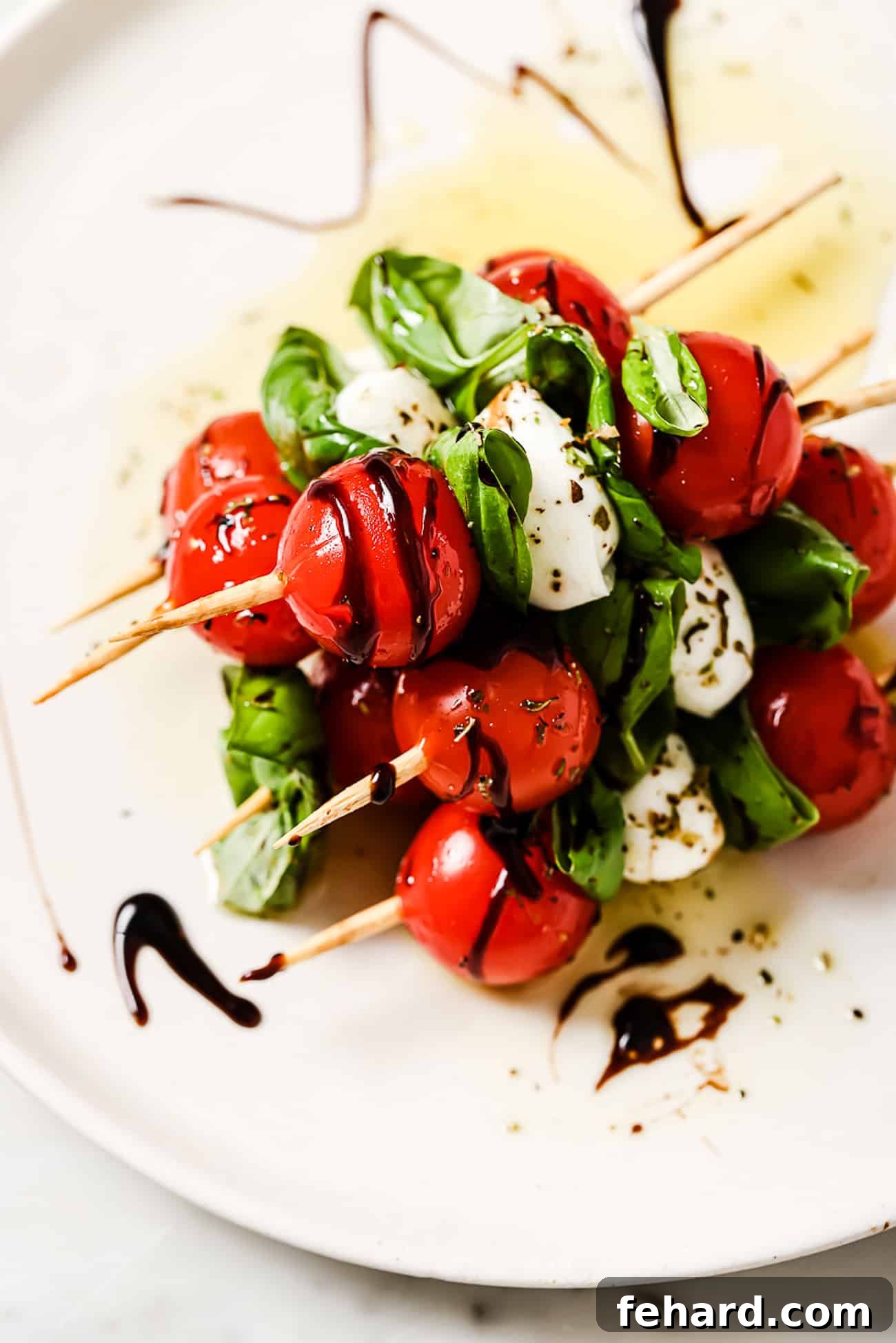 Fresh Caprese Bites 7 Several caprese skewers on a white serving plate.