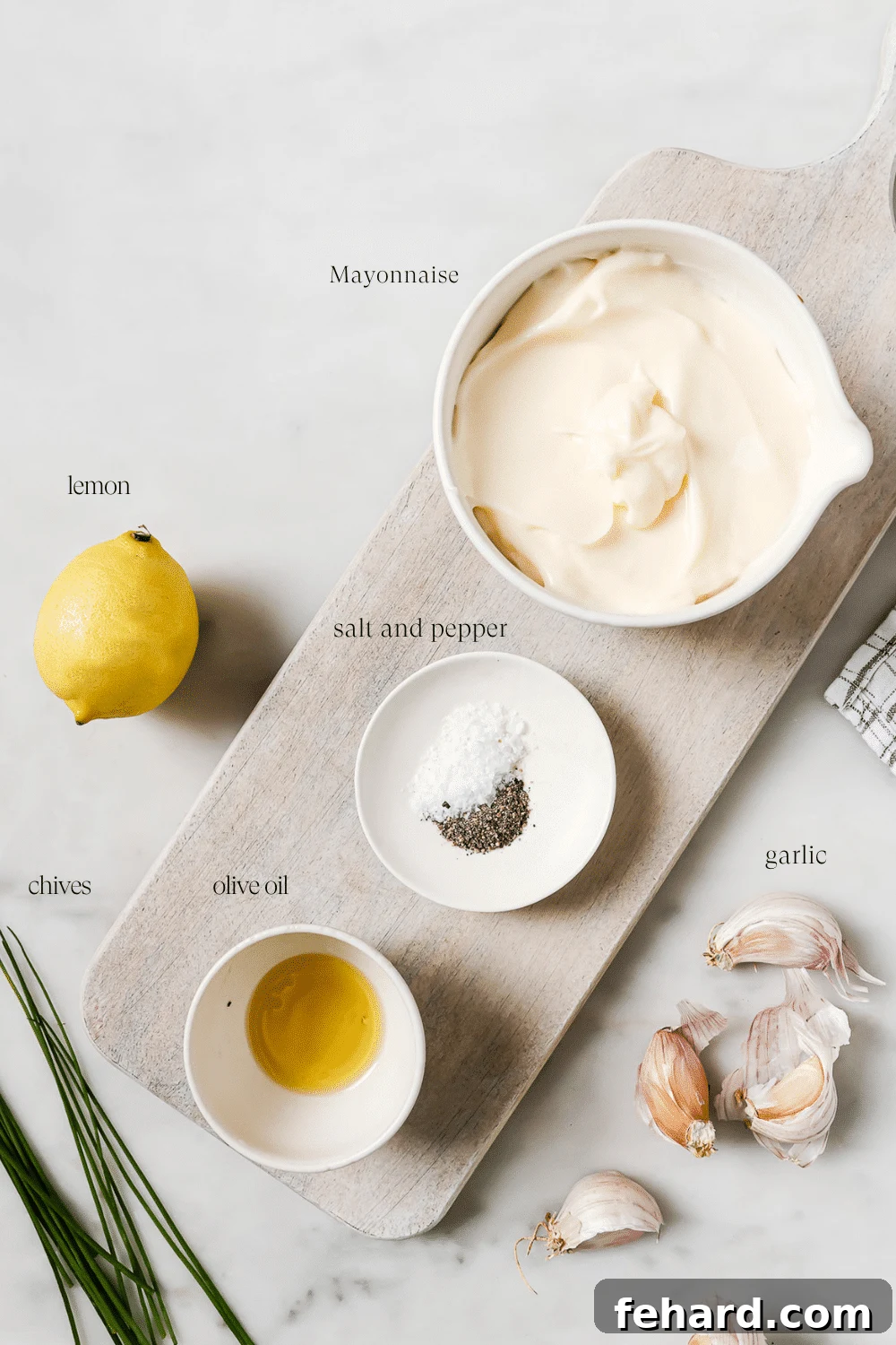 Pre-measured ingredients for homemade garlic aioli neatly arranged on a rustic wooden cutting board, ready for preparation.