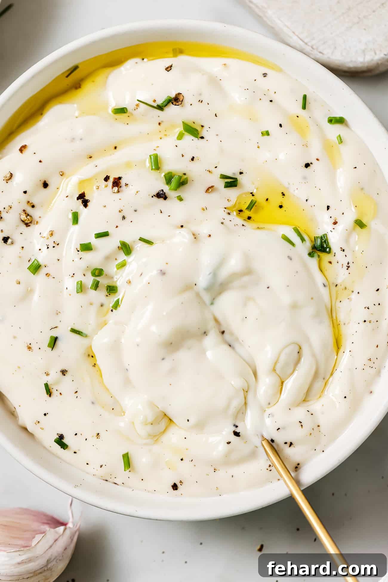 A beautifully presented bowl of creamy garlic aioli, garnished with vibrant chopped chives, ready to be served.