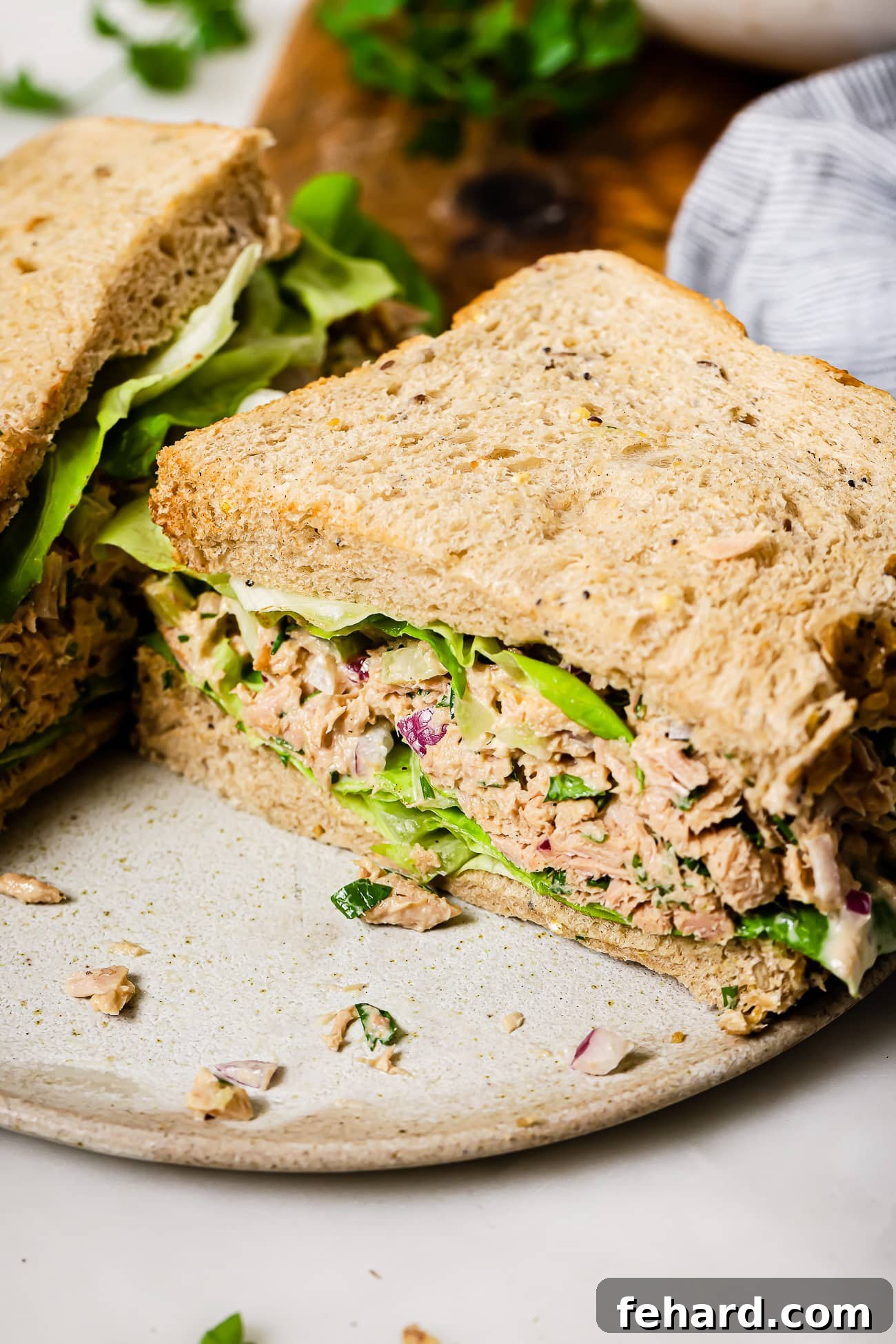 Half of a tuna salad sandwich with lettuce on a plate.