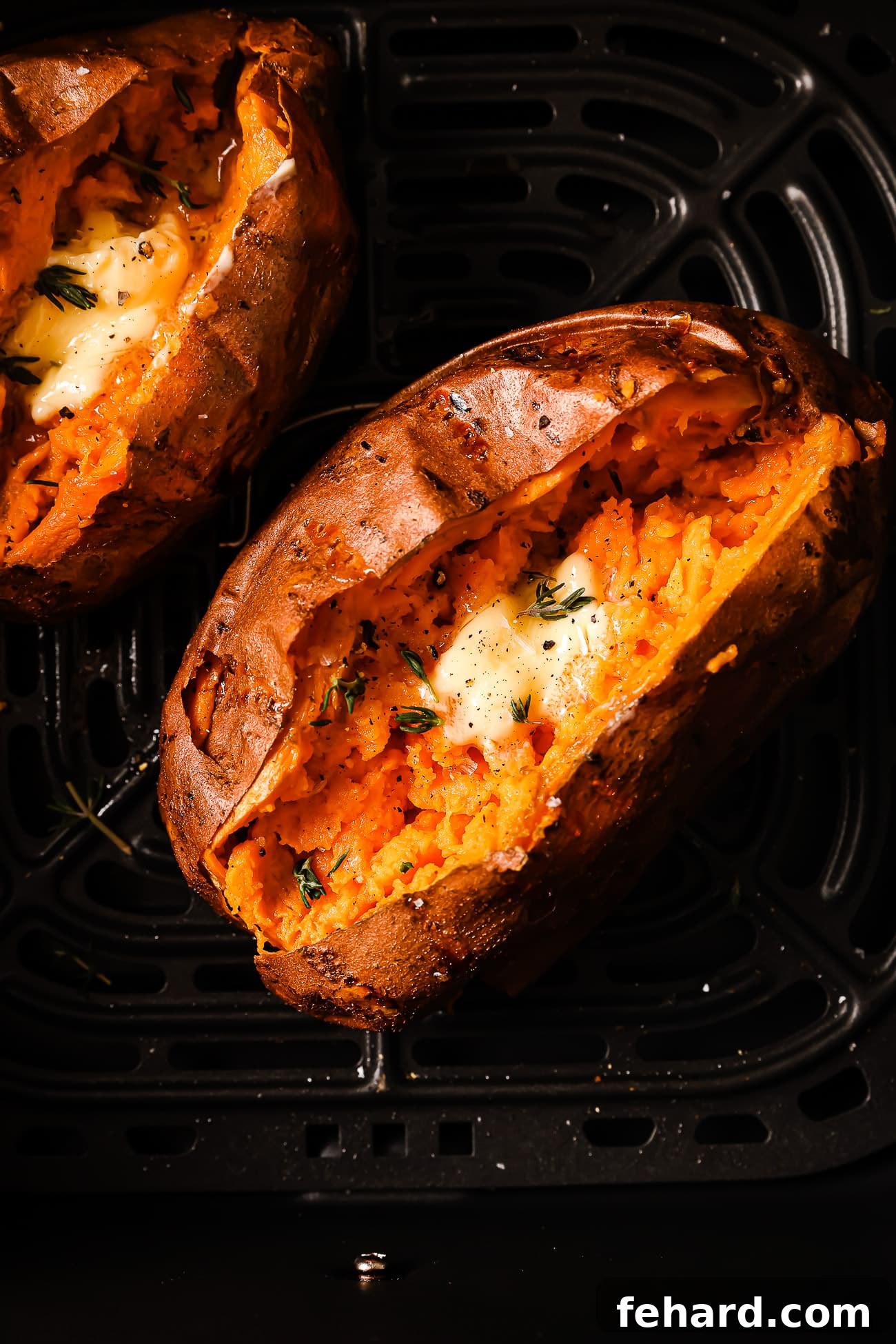 An overhead view of a sweet potato with butter and herbs in the air fryer.