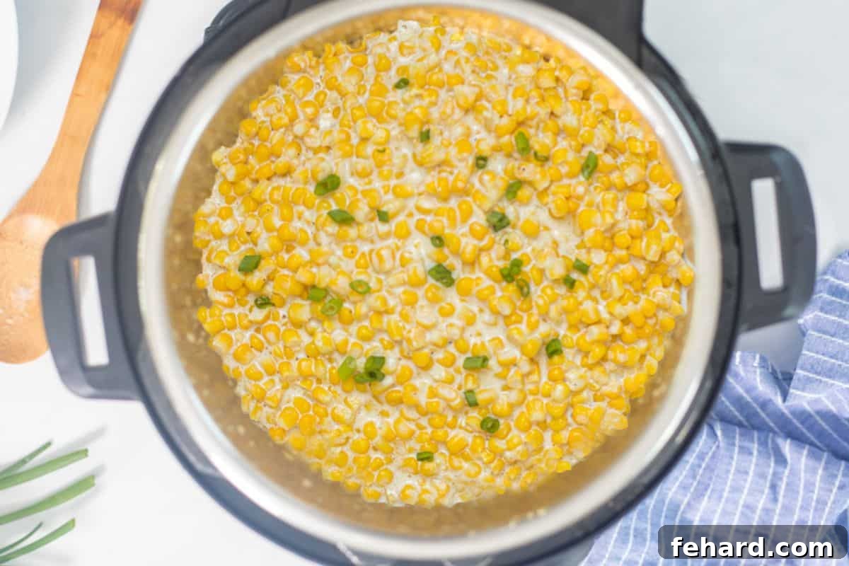 Instant Pot with finished creamed corn, garnished with fresh green onions.
