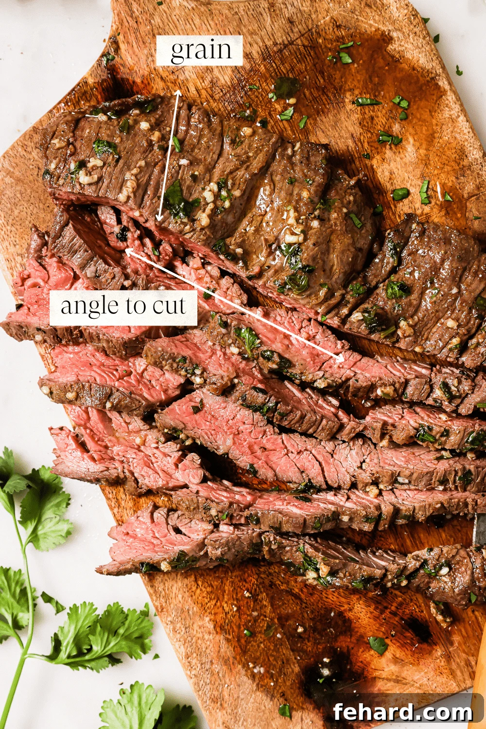 An overhead view of thinly sliced carne asada on a wooden cutting board, ready to serve.