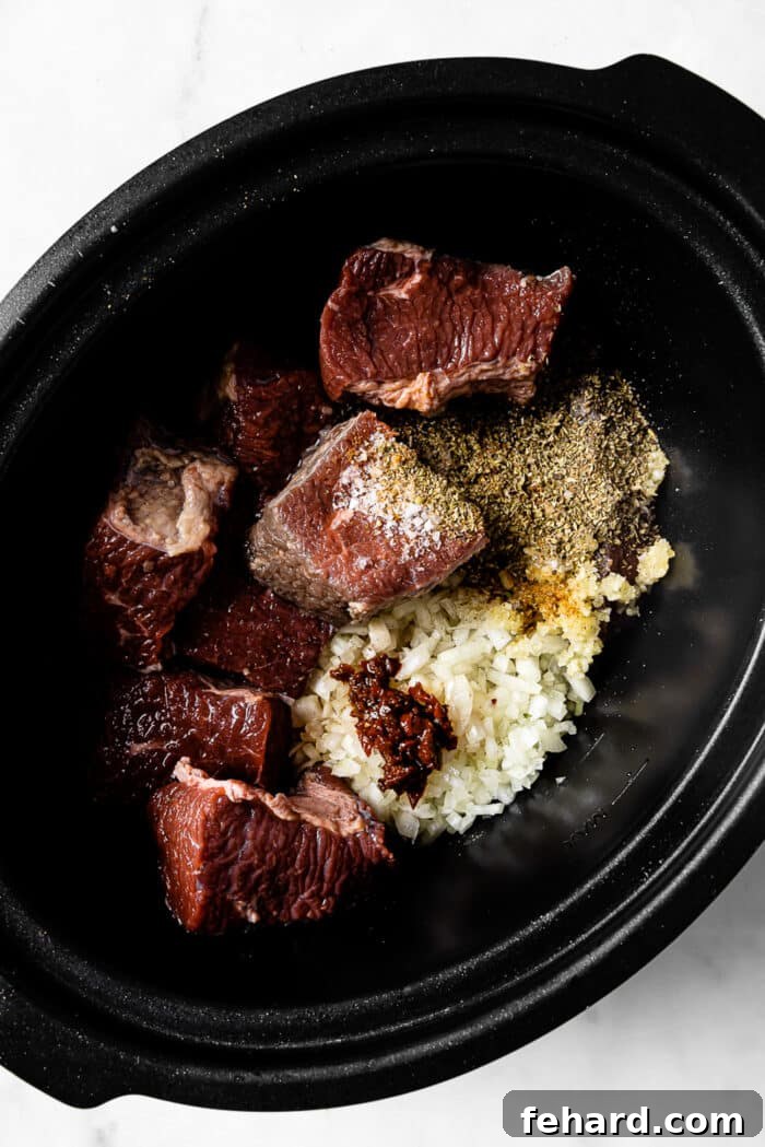 Beef, onions, garlic, and seasonings in a slow cooker.
