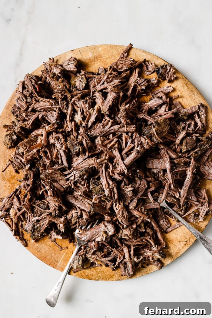 Shredded barbacoa on a wooden cutting board.
