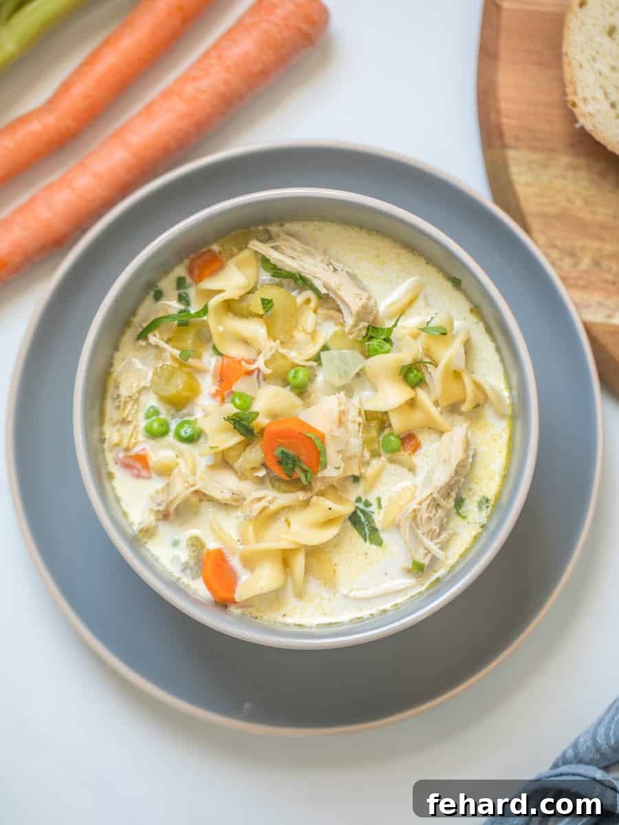 A steaming bowl of Creamy Instant Pot Turkey Noodle Soup, generously garnished with fresh parsley, highlighting the tender egg noodles, vibrant carrots, and peas. Made with delicious leftover turkey.