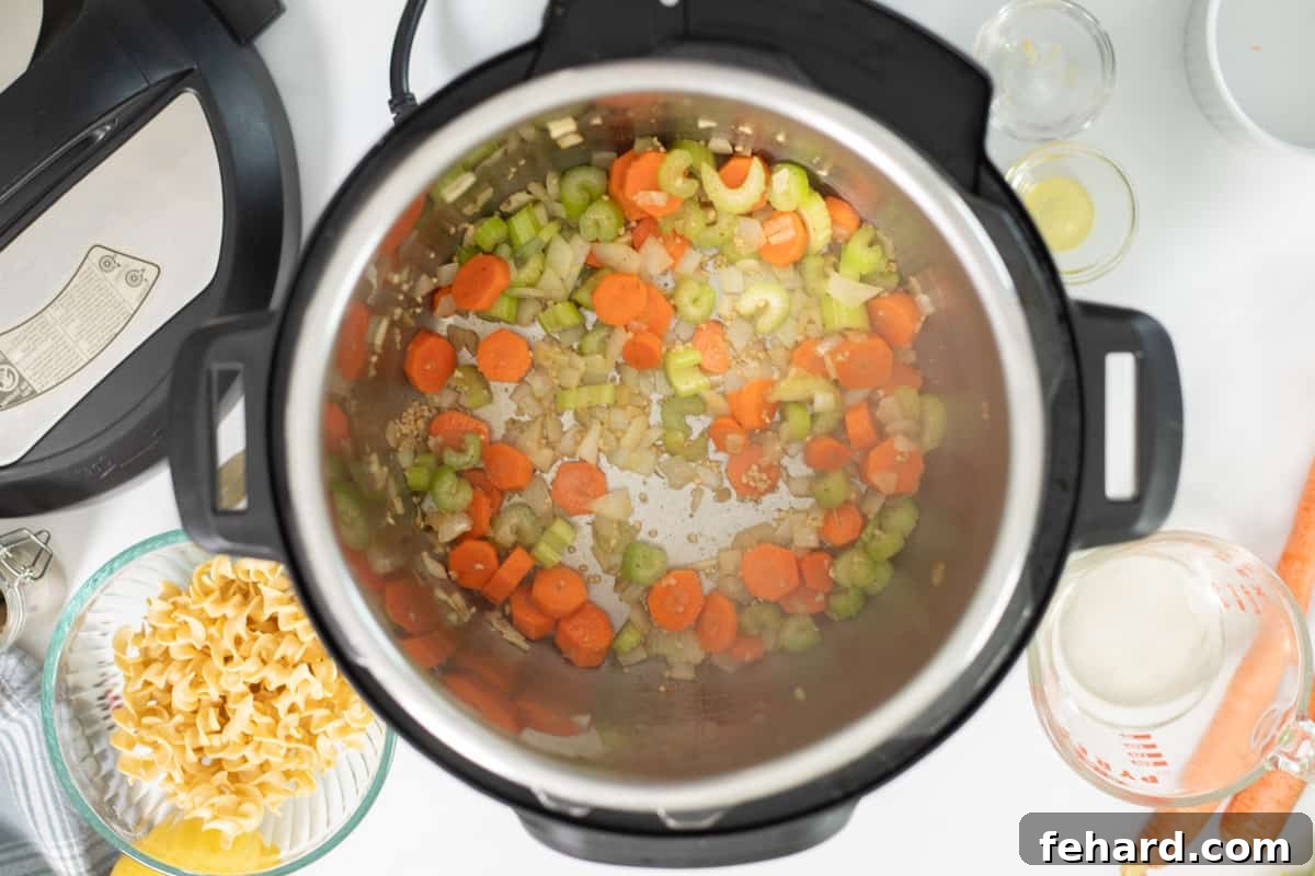 Carrots, onions, celery, and garlic sauteed in pressure cooker with olive oil and butter, forming the aromatic base for turkey noodle soup.
