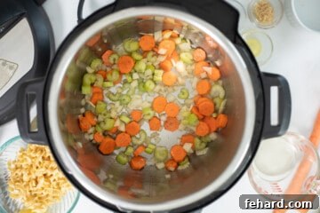 Carrots, onions, celery, and garlic sauteed in pressure cooker with olive oil and butter and ingredients for turkey noodle soup in background.