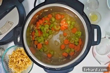 Inner pot after deglazing with white wine with carrots, onions, celery, and garlic sauteed in pressure cooker with olive oil and butter and ingredients for turkey noodle soup in background.