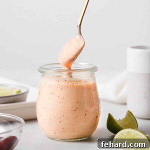 Homemade Smoky Chipotle Sauce 7 A glass jar of chipotle sauce with a spoon in it.
