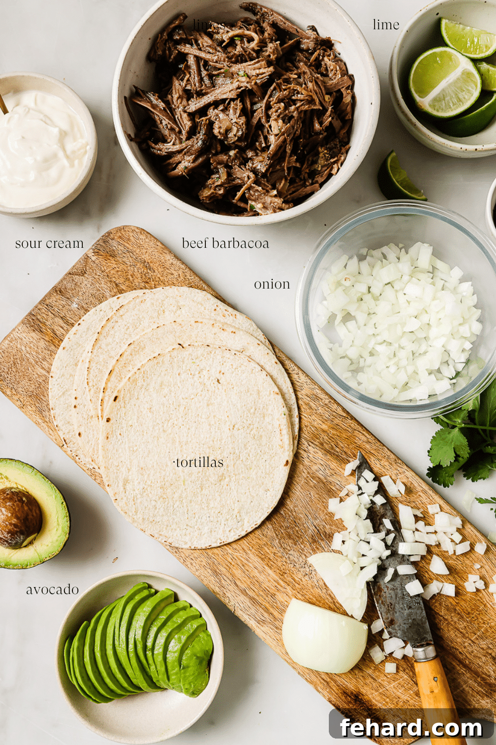 An overhead view of all the fresh, vibrant ingredients for barbacoa tacos arranged in small bowls, including diced onions, cilantro, avocado, and spices.