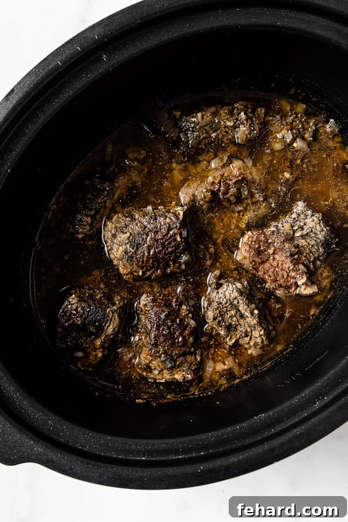 An overhead view of the slow cooker with perfectly cooked, tender beef in a rich sauce.