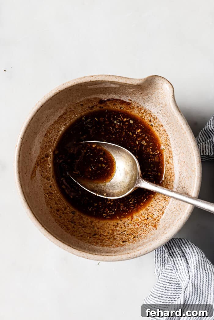 An overhead view of seasonings and olive oil being combined in a mixing bowl. 