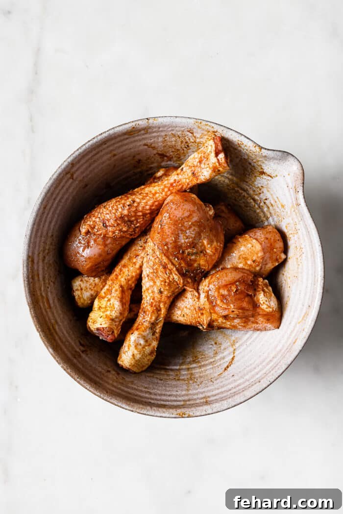 Chicken legs added to the bowl and coated in the seasoning mixture.