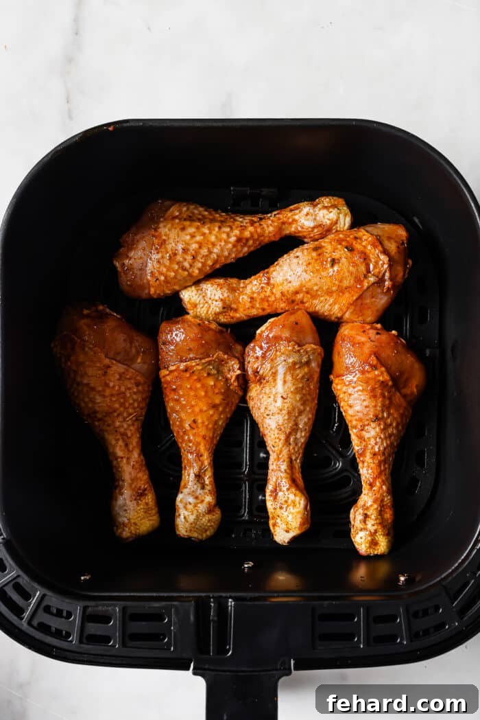 Chicken legs carefully arranged in a single layer in an air fryer basket. 