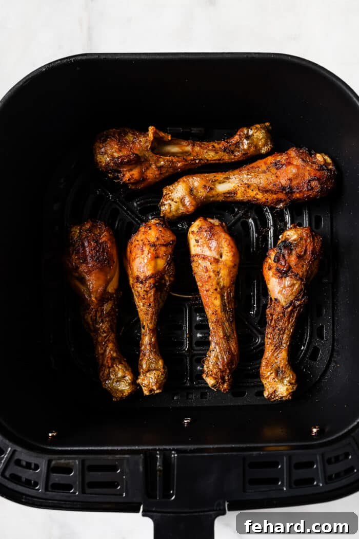 Cooked, golden-brown chicken legs resting in an air fryer basket. 