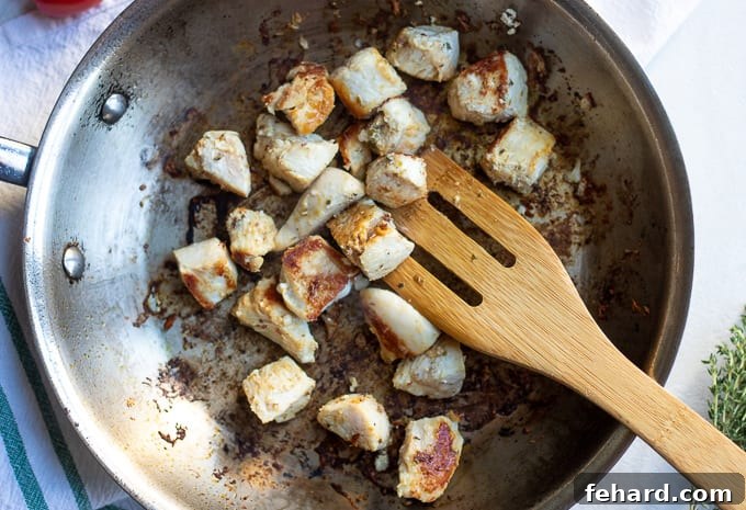 Perfectly browned chicken breast cubes in a hot skillet, ready for the next step.