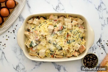 Assembled strata with bread and cheese in casserole dish before adding egg custard.